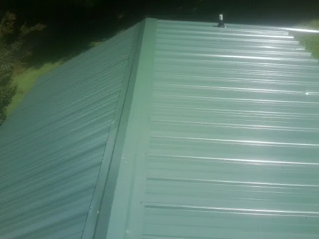 New green metal panels meeting at the ridge of a roof — Flat Roof Repair work by our crew in Ventura