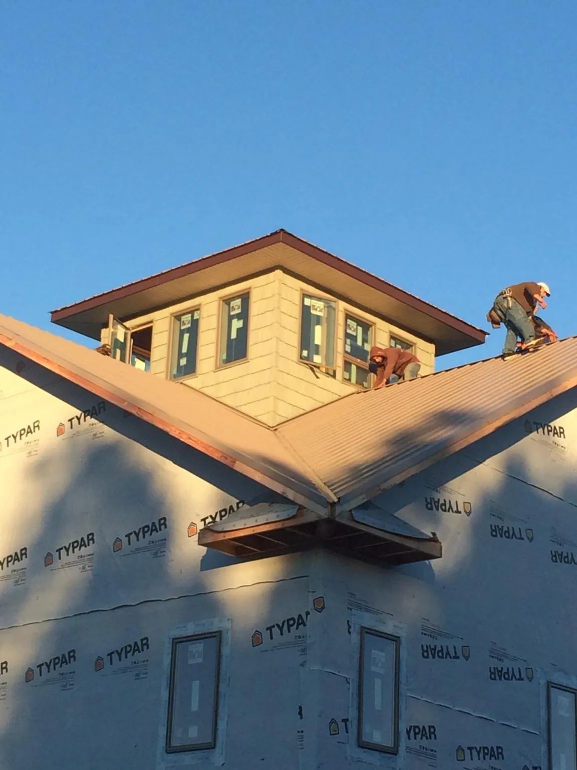 Roofers working around a rooftop cupola on a new metal roof at sunset — Roof Waterproofing in Ventura by Roofing Brothers